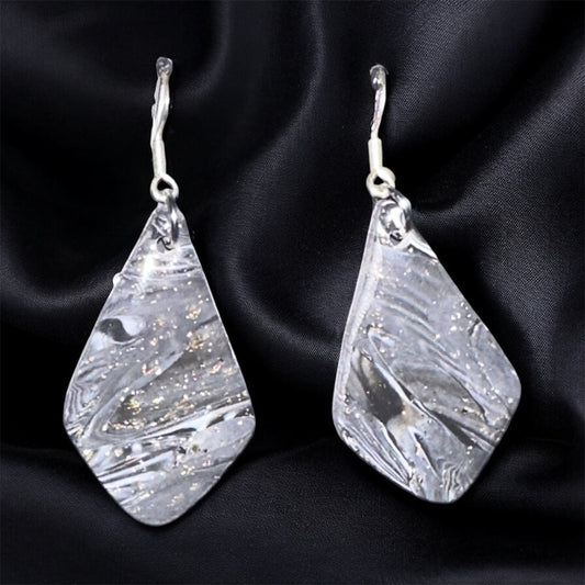 Teardrop-shaped silver earrings on a black satin background